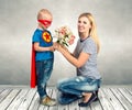 The son in the costume of a superhero gives his mother a bouquet of flowers.