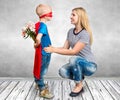 The son in the costume of a superhero gives his mother a bouquet of flowers.