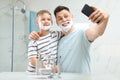 Son and dad with shaving foam on faces taking selfie Royalty Free Stock Photo