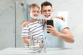 Son and dad with shaving foam on faces taking selfie Royalty Free Stock Photo