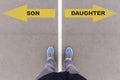 Son or Daughter choice, text on asphalt ground, feet and shoes on floor