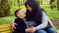 The son gives his mother a fresh bouquet of blue muscari flowers on a bench in the park. Royalty Free Stock Photo