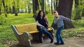 The son gives his mother a fresh bouquet of tulips flowers on a bench in the park. Royalty Free Stock Photo