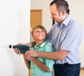 Son helping proud father to drill wall Royalty Free Stock Photo