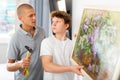 Son helps father to hang the painting on the wall of house Royalty Free Stock Photo