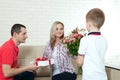 Son hiding bouquet to surprise mommy on mother`s day. Woman, man Royalty Free Stock Photo