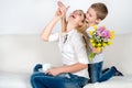 Son holds behind his bouquet of beautiful flowers for his beloved mother.The concept of the celebration,women`s day.