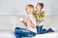 Son holds behind his bouquet of beautiful flowers for his beloved mother.