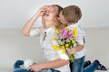 Son holds behind his bouquet of beautiful flowers for his beloved mother.