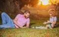 Son laying on grass and playing chess with father. Active people having fun and playing chess at park, spend time with Royalty Free Stock Photo