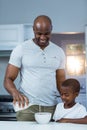 Son looking at father pouring milk in a bowl