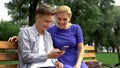 Son and mother sitting on bench watching smartphone photos taken during walk Royalty Free Stock Photo