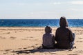 Son and mother sitting turn back on the beach and looking at the sea Royalty Free Stock Photo