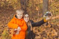 Son and mother are taking selfie on camera in autumn park. Single parent, leisure and fall season concept. Royalty Free Stock Photo