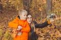 Son and mother are taking selfie on camera in autumn park. Single parent, leisure and fall season concept. Royalty Free Stock Photo