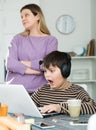 Son plaing video games at laptop, sad mom on background Royalty Free Stock Photo