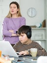 Son plaing video games at laptop, sad mom on background Royalty Free Stock Photo
