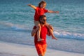 Son sits on fathers shoulders piggyback ride. Dad and kid son walking on the beach at the day time. Happy family Royalty Free Stock Photo