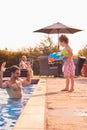 Son Squirting Father With Water Pistol Playing In Swimming Pool On Summer Vacation