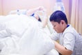 The son is taking care of the sick mother on the hospital bed. The boy is massaging his mother`s legs. female patients lying in