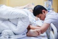 The son is taking care of the sick mother on the hospital bed. The boy is massaging his mother`s legs. female patients lying in