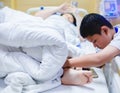 The son is taking care of the sick mother on the hospital bed. The boy is massaging his mother`s legs. female patients lying in