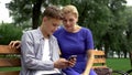 Son teaching mother to use application on smartphone, new technologies, gadget