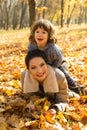 Son on top her mother in autumn park Royalty Free Stock Photo