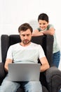 Son watching father using laptop in living room