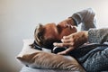 This song just takes me places. a handsome young man listening to music on his headphones while relaxing in bed at home. Royalty Free Stock Photo