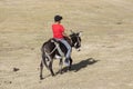 Song Kul, Kyrgyzstan, August 8 2018: A boy in a red T-shirt rides a donkey through the steppe at Song Kul Lake in Kyrgyzstan