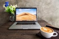 Latte art coffee with macbook computer on wooden table