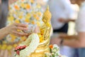 Songkran festival, Thai New Year. female hand holding silver bowl pouring water with jasmine and roses onto buddha statue Royalty Free Stock Photo