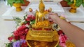 Songkran Thai woman pours water on a golden Buddha image with her hands Royalty Free Stock Photo