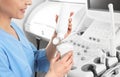 Sonographer covering ultrasound machine probe with gel in clinic