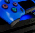 Sony black Playstation 4 Pro game console and blue wireless controller Royalty Free Stock Photo