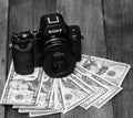 Sony a7 mirrorless camera with 35mm mounted lens, camera on dollars money. Making money with photography. Bucharest, Romania, 2020