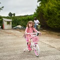 Soon shell be riding without training wheels. Portrait of an adorable little girl riding her bike with her brother Royalty Free Stock Photo