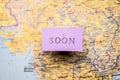 Soon stencil text on purple paper over a map.. Royalty Free Stock Photo
