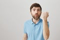 Soon you will meet with my fist. Studio shot of angry caucasian bearded male raising fist and threaten person, frowning