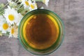 Soothing chamomile tea in a glass. Bouquet of daisy flowers on a wooden table. Top view Royalty Free Stock Photo