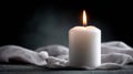 Soothing glow of lit white candle on dark background with draped fabric Royalty Free Stock Photo