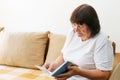 Soothing reading. Portrait of thoughtful elderly woman reading her favorite Royalty Free Stock Photo