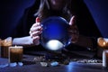 Soothsayer using crystal ball to predict future at table in darkness. Fortune telling Royalty Free Stock Photo