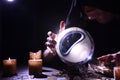 Soothsayer using crystal ball to predict future at table in darkness, closeup. Fortune telling Royalty Free Stock Photo