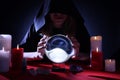 Soothsayer using crystal ball to predict future at table in darkness. Fortune telling Royalty Free Stock Photo