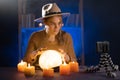 Soothsayer using crystal ball to predict future at table in darkness, having online spiritual seance use cell phone Royalty Free Stock Photo