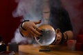 Soothsayer using crystal ball to predict future at table indoors, closeup Royalty Free Stock Photo