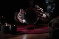 Soothsayer using crystal ball to predict future at table indoors, closeup Royalty Free Stock Photo