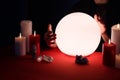 Soothsayer using glowing crystal ball to predict future  at table in darkness, closeup. Fortune telling Royalty Free Stock Photo